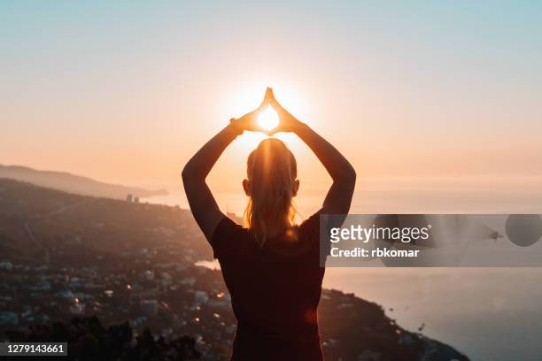 silhouette of woman doing yoga at sunrise - happy woman in early morning sunlight stock-fotos und bilder
