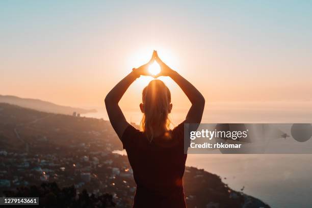 silhouette of woman doing yoga at sunrise - buddhism fotografías e imágenes de stock