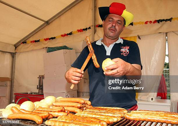 An employee serves Bratwurst during an outdoor festival to celebrate German Unity Day on the 21st anniversary of German reunification on October 3,...