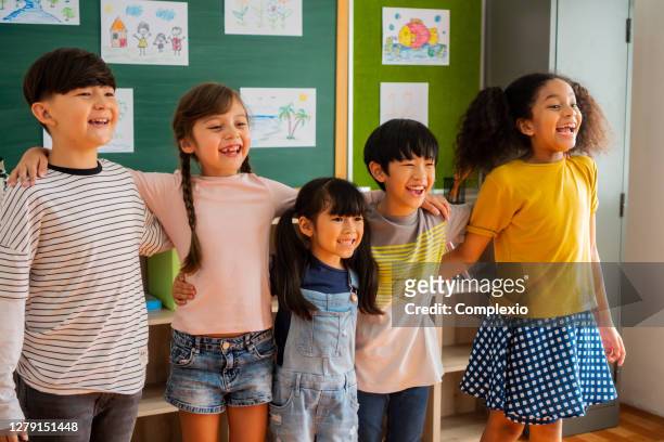porträt von schulkindern, die im klassenzimmer lächeln - singapore school stock-fotos und bilder