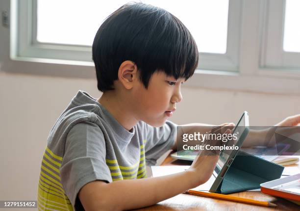 asian school boy using digital device in school classroom, digital native, technology, learning, touchscreen. male elementary student with tablet in class - chinese student laptop stock pictures, royalty-free photos & images