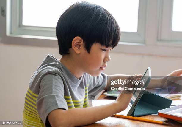 asian school boy using digital device in school classroom, digital native, technology, learning, touchscreen. male elementary student with tablet in class - japanese boys stock pictures, royalty-free photos & images