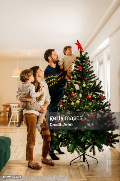 familia decorando árbol de navidad - christmas family fotografías e imágenes de stock