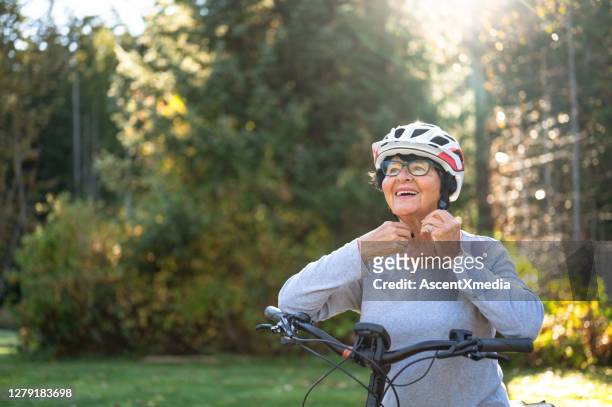 hogere vrouw die haar fietsenhelm knikt - elektrische motor stockfoto's en -beelden
