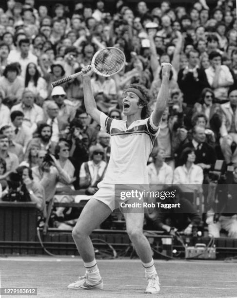 John McEnroe of the United States raises his racquet aloft on Centre Court in celebration after defeating Bjorn Borg to win the Men's Singles Final...