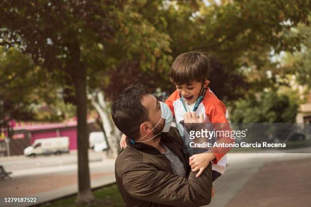 father plays with his children in the park during the covid-19 pandemic, removing mask. - play off stock pictures, royalty-free photos & images