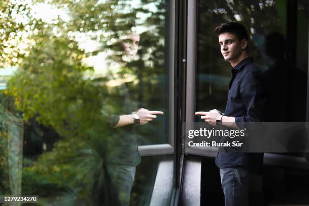 glücklicher junger geschäftsmann sms vor dem fenster - green glass business stock-fotos und bilder