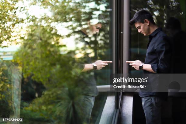 jeune homme d’affaires heureux textos devant la fenêtre - effet miroir homme photos et images de collection