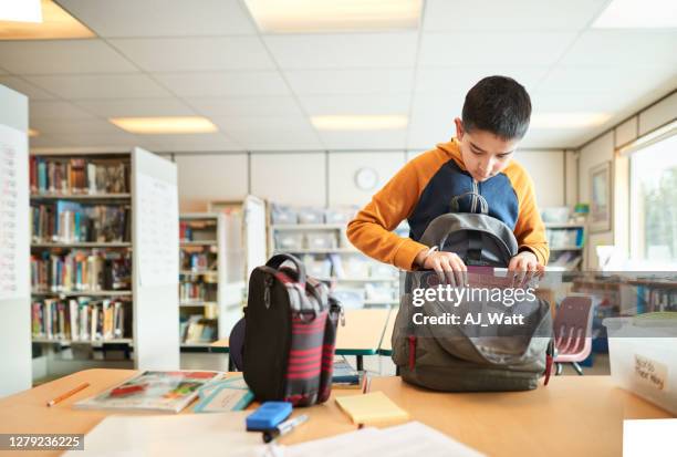 inpakken van zijn schooltas na de klas - packing kids backpack stockfoto's en -beelden