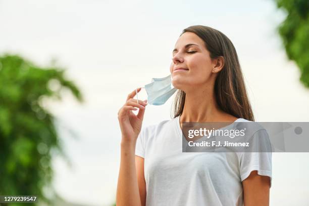 happy woman taking off mask to breathe - pollution mask stock pictures, royalty-free photos & images