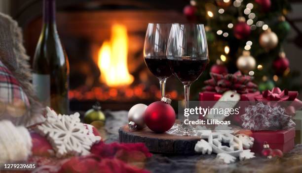 vino rosso di natale e un regalo davanti a un camino. - red wine foto e immagini stock