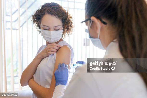 enfermera aplicando la vacuna al paciente en casa - vacuna contra la covid 19 fotografías e imágenes de stock