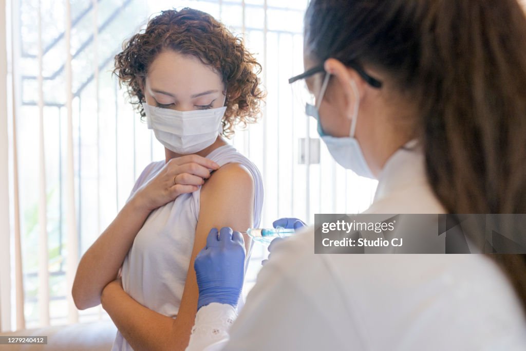 Nurse applying vaccine to patient at home