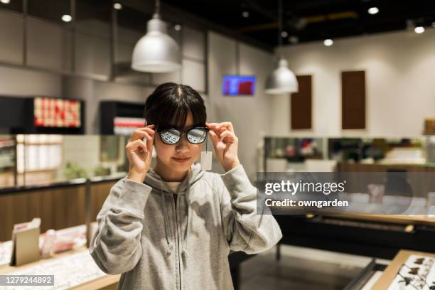 girl trying on new eyeglasses - asian child with new glasses ストックフォトと画像