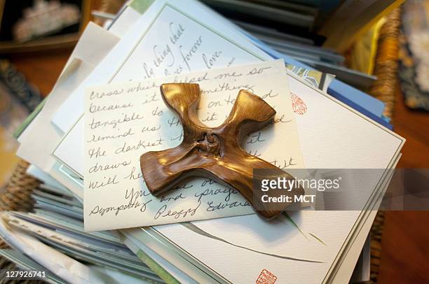 Stack of letters and cards and a small wooden cross sent by well-wishers to the family of slain law student Lauren Giddings sits on a table.