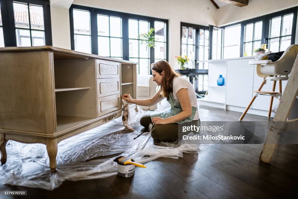 Jonge vrouw die een oud meubilair herstelt en thuis geniet