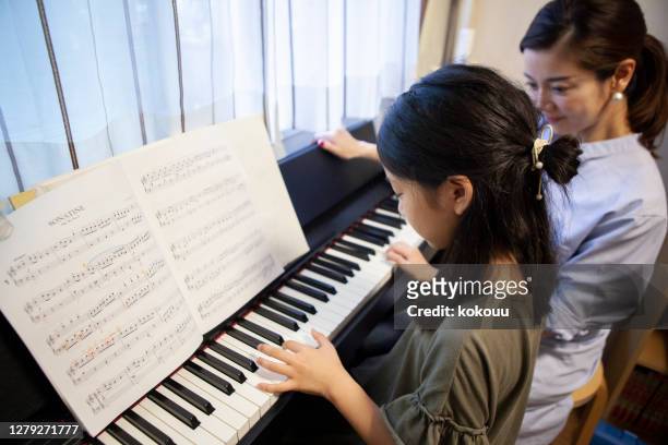 母親とピアノのレッスンを受ける娘 - ピアノ ストックフォトと画像