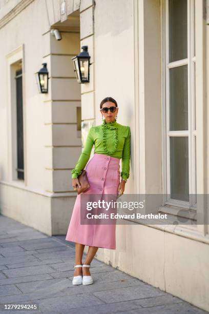 Gabriella Berdugo wears a total look Prada, a green ruffle blouse with long sleeves, a pink pencil midi skirt with pockets, a brown leather pouch /...