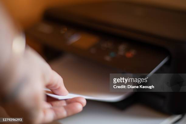 picking up the paper from the home office printer - printer stock pictures, royalty-free photos & images