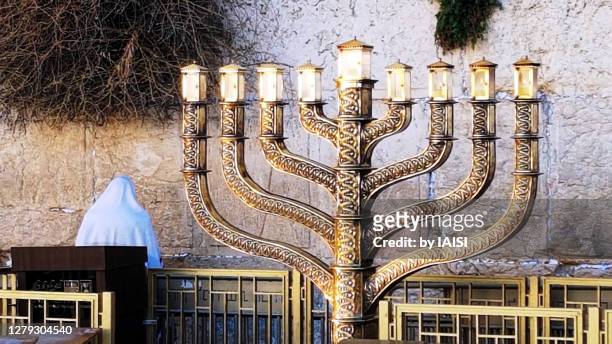 close-up of huge hanukkiah / the nine-branched menorah for hanukkah - and praying man at the western wall, jerusalem the old city - charedisches judentum stock-fotos und bilder