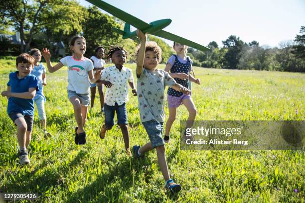 children running through a field with model plane - communities public park stock pictures, royalty-free photos & images
