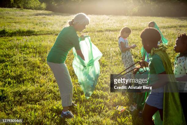 young green activists picking up litter in nature - summer super 8 stockfoto's en -beelden