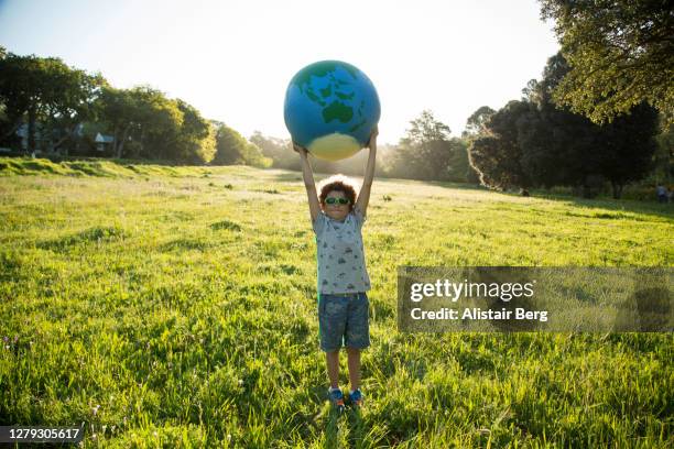 boy holding up a large globe outdoors - summer super 8 stockfoto's en -beelden