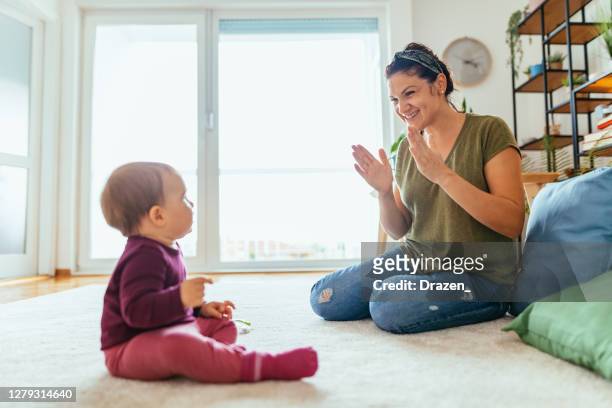babá brincando com menina em casa - mulher mostrando como bater palmas para o bebê - cantar - fotografias e filmes do acervo