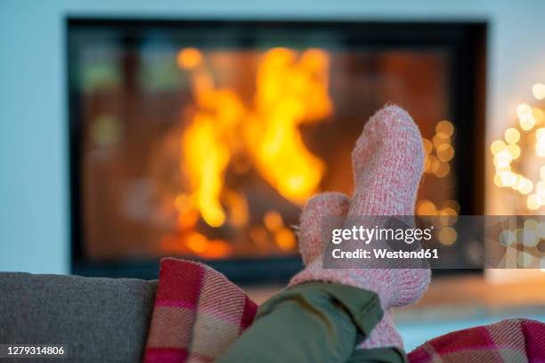 legs of young woman wearing socks relaxing against fireplace at home - stocking feet fotografías e imágenes de stock