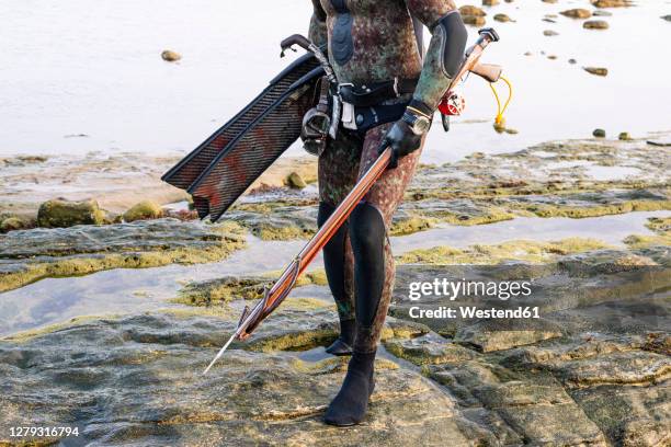 mature man holding harpoon while standing at beach - harpoon stock pictures, royalty-free photos & images