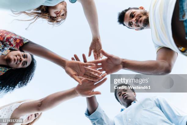 low angle view of friends bring their hands together in show of unity before playing game - game show stock pictures, royalty-free photos & images