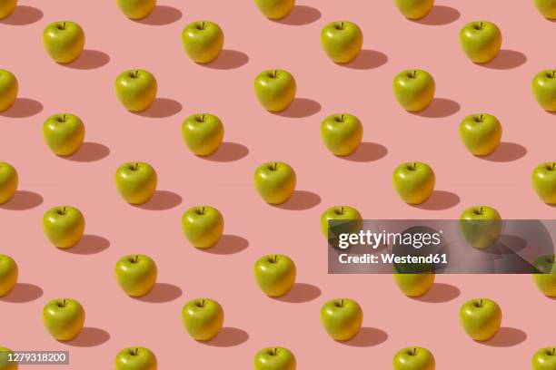 pattern of green apples against pink background - repetition pattern stock pictures, royalty-free photos & images