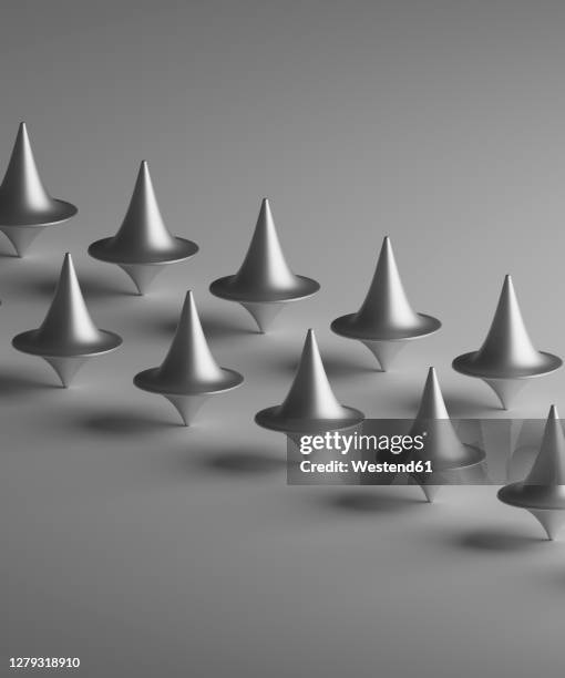 three dimensional render of rows of metallic spinning tops - spinning top stock illustrations