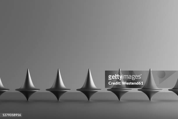three dimensional render of row of metallic spinning tops - spinning top stock illustrations