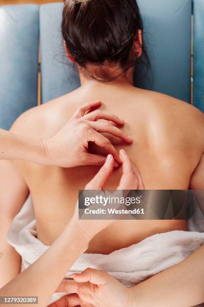 physiotherapist inserting needle on woman back lying on table - agopuntura foto e immagini stock