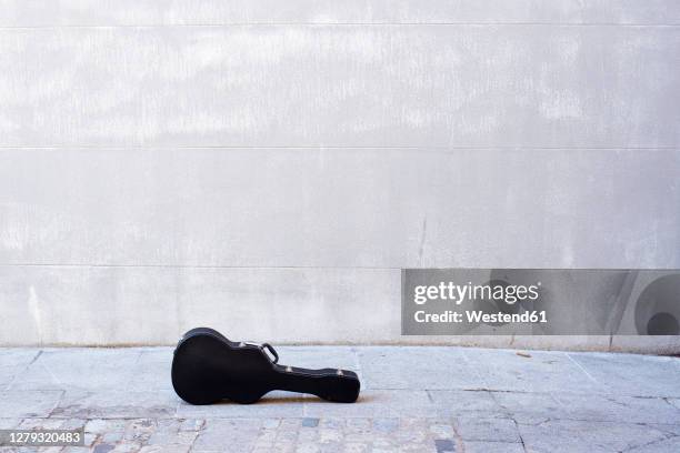 guitar kept on road against concrete wall in city - guitar case fotografías e imágenes de stock