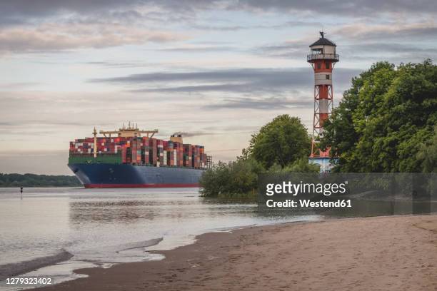 germany, hamburg, container ship on elbe river and wittenbergen lighthouse at sunset - elbe bildbanksfoton och bilder