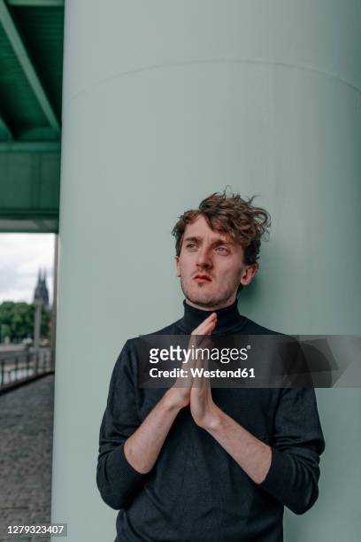 thoughtful depressed young man standing against column in city - dreiviertelansicht stock-fotos und bilder
