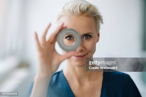 close-up of smiling businesswoman looking through object in office - figura mujer fotografías e imágenes de stock