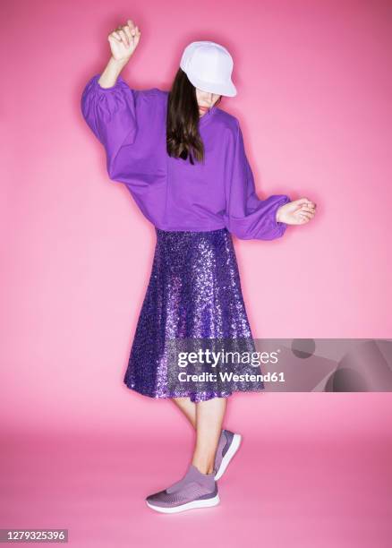 fashion model wearing cap posing against pink background - purple skirt fotografías e imágenes de stock