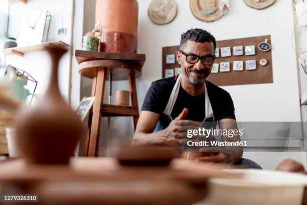 smiling male artist making pottery in workshop - pottery stock-fotos und bilder