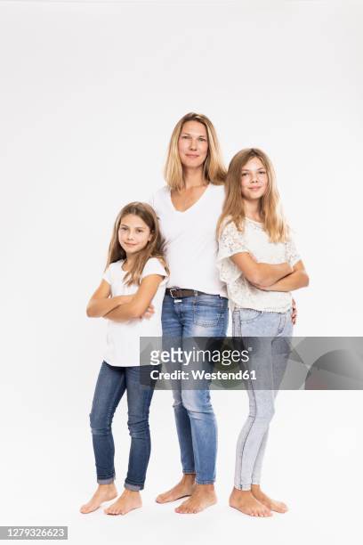 mother with daughters standing against white background - kids standing crossed arms stock-fotos und bilder