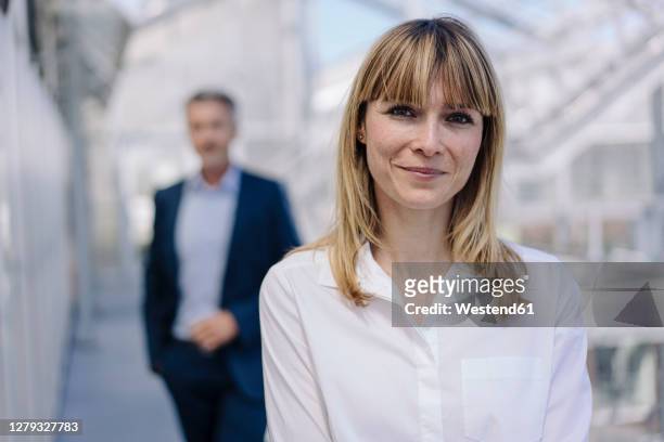 close-up of smiling businesswoman with male coworker in background at greenhouse - portrait business partners stock-fotos und bilder