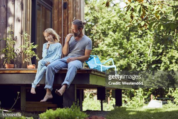 father and daughter brushing teeth while sitting outside tiny house - family in front of house stock-fotos und bilder