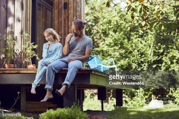 father and daughter brushing teeth while sitting outside tiny house - dental bonding stock pictures, royalty-free photos & images