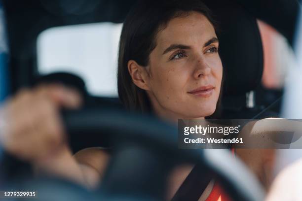 thoughtful woman driving car - guidare foto e immagini stock