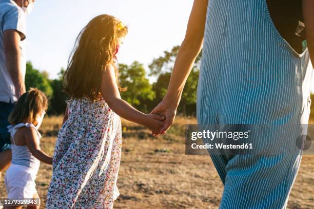 family holding hands and walking on land - mother daughter holding hands stock pictures, royalty-free photos & images