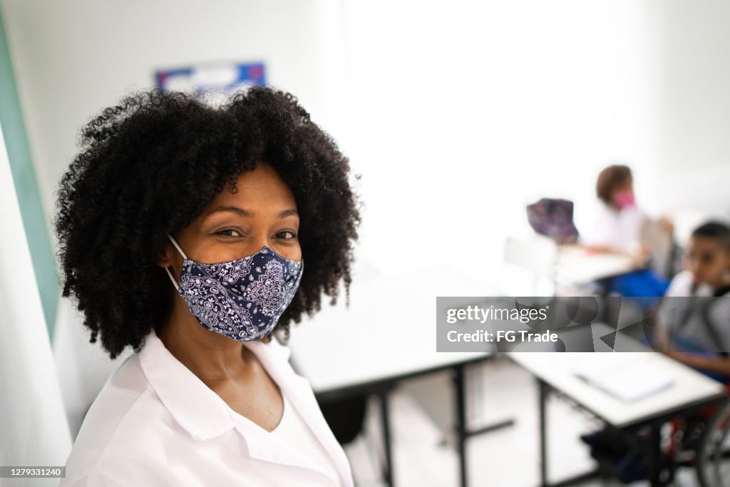 Verticale de l’enseignant travaillant dans la salle de classe utilisant le masque de visage