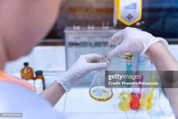 close up of female hands in sterile gloves pouring yellow liquid into glass tube in oil laboratory experimental concept of oil industry - food additive stock pictures, royalty-free photos & images