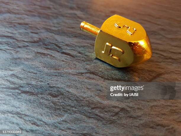 close-up of single gold-colored spinning top, a hanukkah game - dreidel stock pictures, royalty-free photos & images